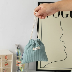 Close-up of gray-blue corduroy drawstring pouch with white cotton ties and fabric label