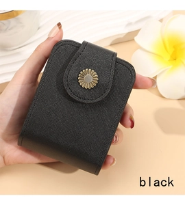 Close-up of black cross-grain leather makeup bag with gold daisy clasp held by hand