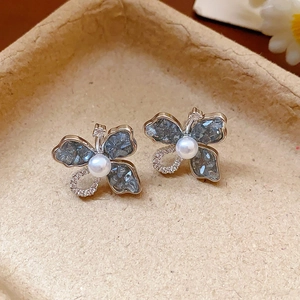 Détail macro de boucles d'oreilles papillon argentées avec cristaux gris et perles blanches
