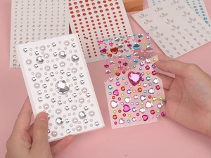 Close-up of colorful heart-shaped rhinestones and white pearls for eye makeup stickers