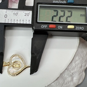 Digital caliper measuring the 22.2 mm width of a gold heart pendant with white shell inlay