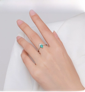 Close-up of crown-shaped S925 silver ring with a pear-cut green gemstone on a finger