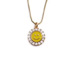 Golden smiley face necklace for women with sparkling stones and enamel on white background