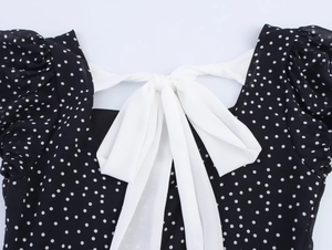 Detail of elegant white bow tie on back of French style black polka dot dress