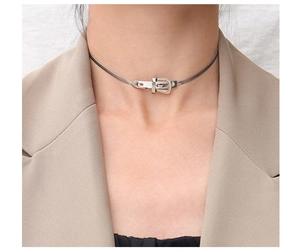 Detailed close-up of a silver belt buckle choker necklace worn by a fashion model
