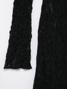 Macro view of textured lace fabric detail with floral patterns on black evening dress
