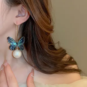 Elegant butterfly pendant earrings with navy resin and large pearl on gold hooks