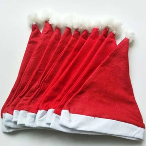 Stack of classic red non-woven Christmas hats with white plush trim and pom poms