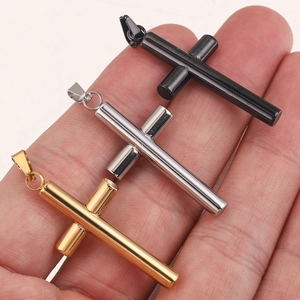 Close-up of gold, silver, and black cross pendants held in hand to show scale