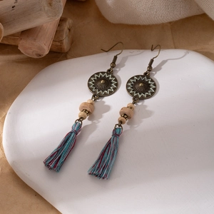 Detail showing bohemian tassel earrings with bronze metal, wood beads and turquoise cotton fringe