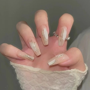 Macro detail of long coffin nails with nude base, white strokes and gold wire accents