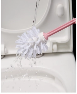 Close-up of pink toilet brush head with white bristles being rinsed under water flow