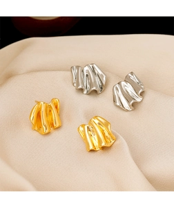Detail view of gold and silver irregular pleated earrings with high-polished metal finish