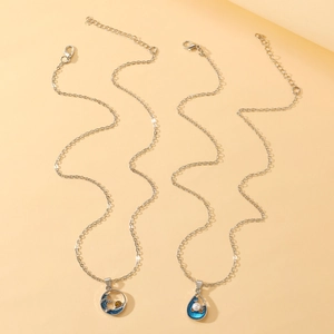 Detailed view of silver wave pendants with blue enamel and pearl on an orange surface