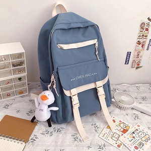 Detail of grey-blue canvas school backpack with cute duck plush and stationery setup