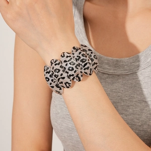 Detail of a vintage leopard print resin bangle worn by a model in natural indoor lighting
