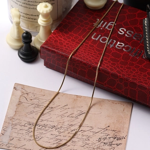 Close-up of golden stainless steel snake bone chain with fine texture on vintage red background