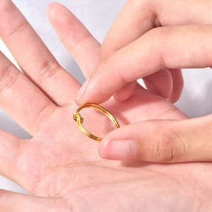 Minimalist 18k gold plated stainless steel knot ring held by hand for detailed view