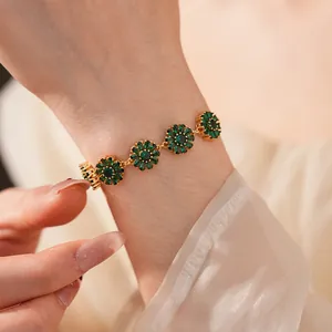 Close-up of a gold-plated flower bracelet featuring green zircon daisies on a female wrist