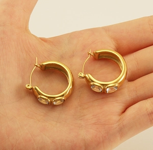 Detail of 18K gold plated hoop earrings with rectangular zircon on hand