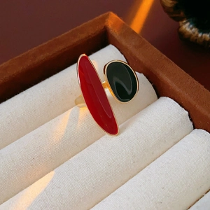 Detailed view of red and green enamel geometric open ring on white velvet jewelry box