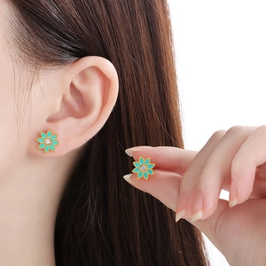 Vue macro de boucles d'oreilles marguerites bleu canard et zircon sur l'oreille