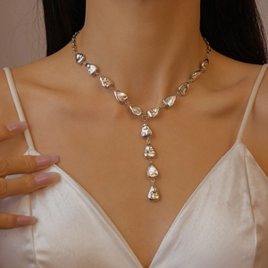 Detail of silver Y-shaped liquid metal necklace on model with white satin top
