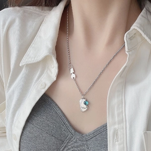Silver lucky necklace with blue zircon stone pendant on a woman wearing white shirt