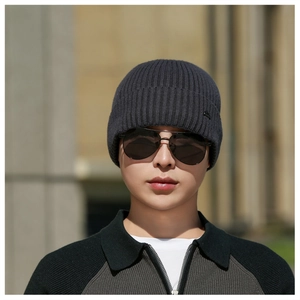 Close-up of charcoal grey ribbed knit beanie with thick fold and small metal decorative tag