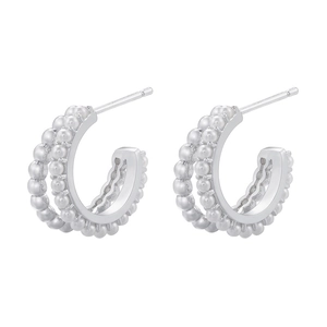 Detail of silver C-shaped hoop earrings featuring triple-row metallic beads on a white background