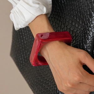 Close-up of translucent red resin geometric square bracelet with ink flow texture