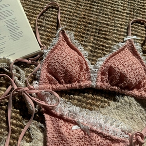 Detailed macro view of pink crochet bikini set with white lace trim and ribbon bows