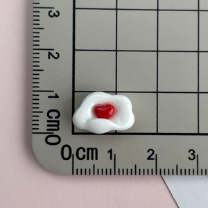 Close-up of a mini white resin cloud with red heart, measuring 1.5 cm on a grid mat