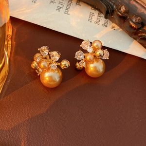 Macro shot of gold floral pearl earrings with zircon crystals on a vintage leather surface