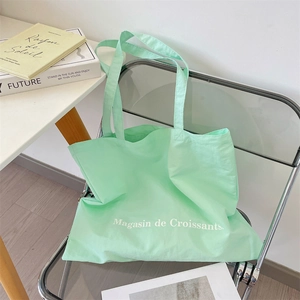 Detail view of mint green canvas tote bag with Magasin de Croissants print on a chair