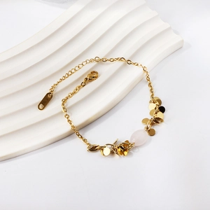 Elegant gold bead bracelet with pink gemstone and round charms on a white background