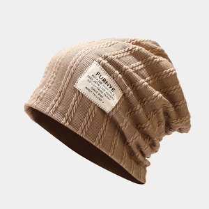 Close-up of cable knit beanie texture with a vintage woven brand patch in light brown