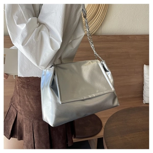 Close-up of silver metallic chain shoulder bag with a glossy finish and flap closure