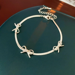 Detailed close-up of silver bow bracelet with snake chain and adjustable lobster clasp