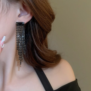 Detail of long black tassel earrings with sparkling crystals worn by a model