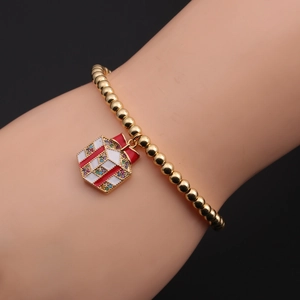 Dettaglio di un bracciale a sfere dorate con ciondolo a forma di pacchetto regalo