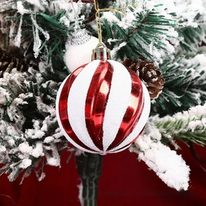 Close-up of red and white striped Christmas ball with snow glitter on a winter tree