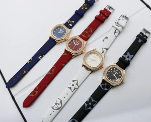 Close-up of square diamond-set quartz watches with leather straps and monogram patterns