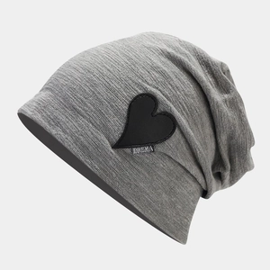 Detail of grey knitted beanie featuring black heart patch with DREMA text embroidery