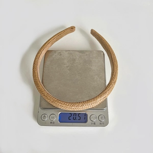 Detailed view of beige woven straw headband on scale weighing approximately 20.51g