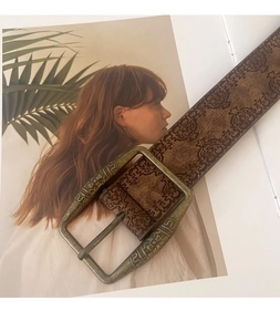 Close-up of vintage embossed leather belt in dark brown with aged bronze metal buckle detail