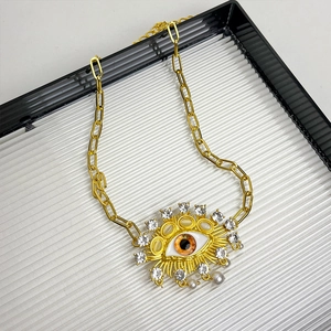 Macro detail of vintage gold evil eye necklace with brown eye inlay and pearls