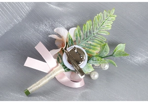 Close-up of wedding corsage back with silver safety pin, alligator clip and champagne ribbon