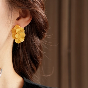 Gros plan d'un clou d'oreille fleur plaqué or 18 carats porté par un mannequin