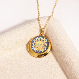 Detailed close-up of a golden necklace featuring a round pendant with a vintage sun face design